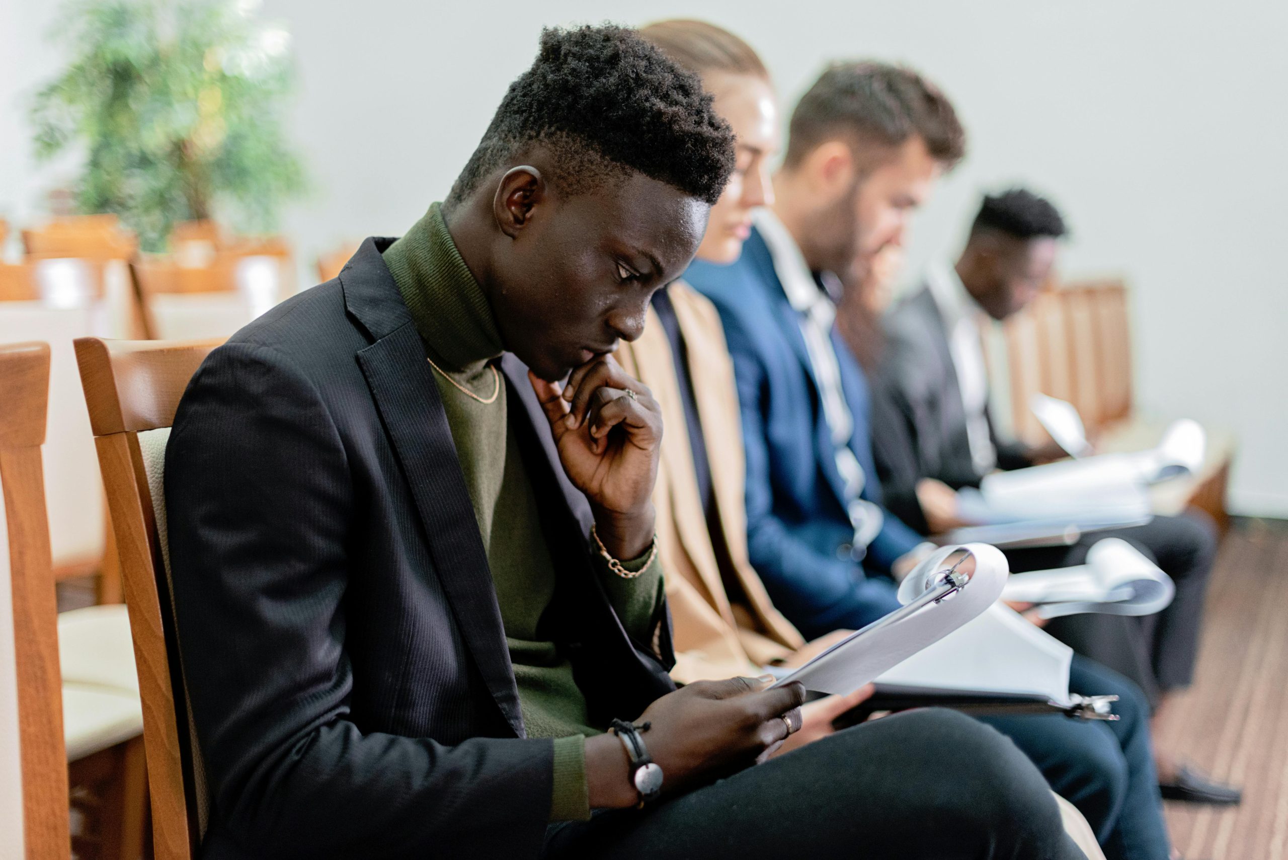 Four diverse professionals in a focused business meeting, reviewing documents in an office setting.